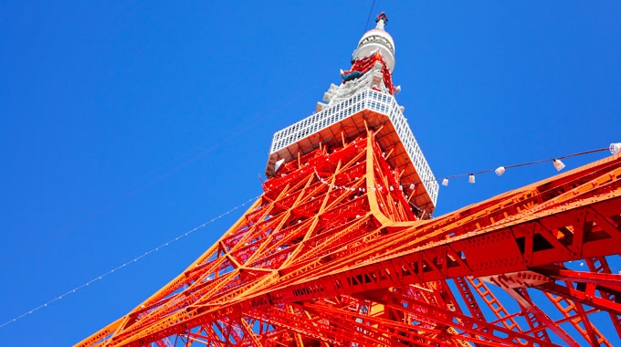Balcon et structure de la Tour Eiffel en gros plan contre un ciel bleu clair.